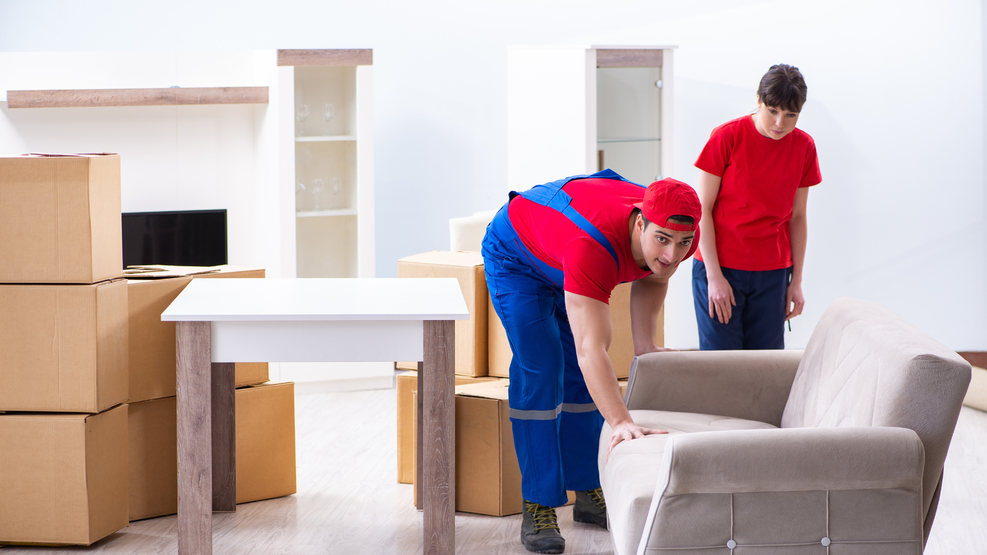 Two men are moving a couch in a living room.