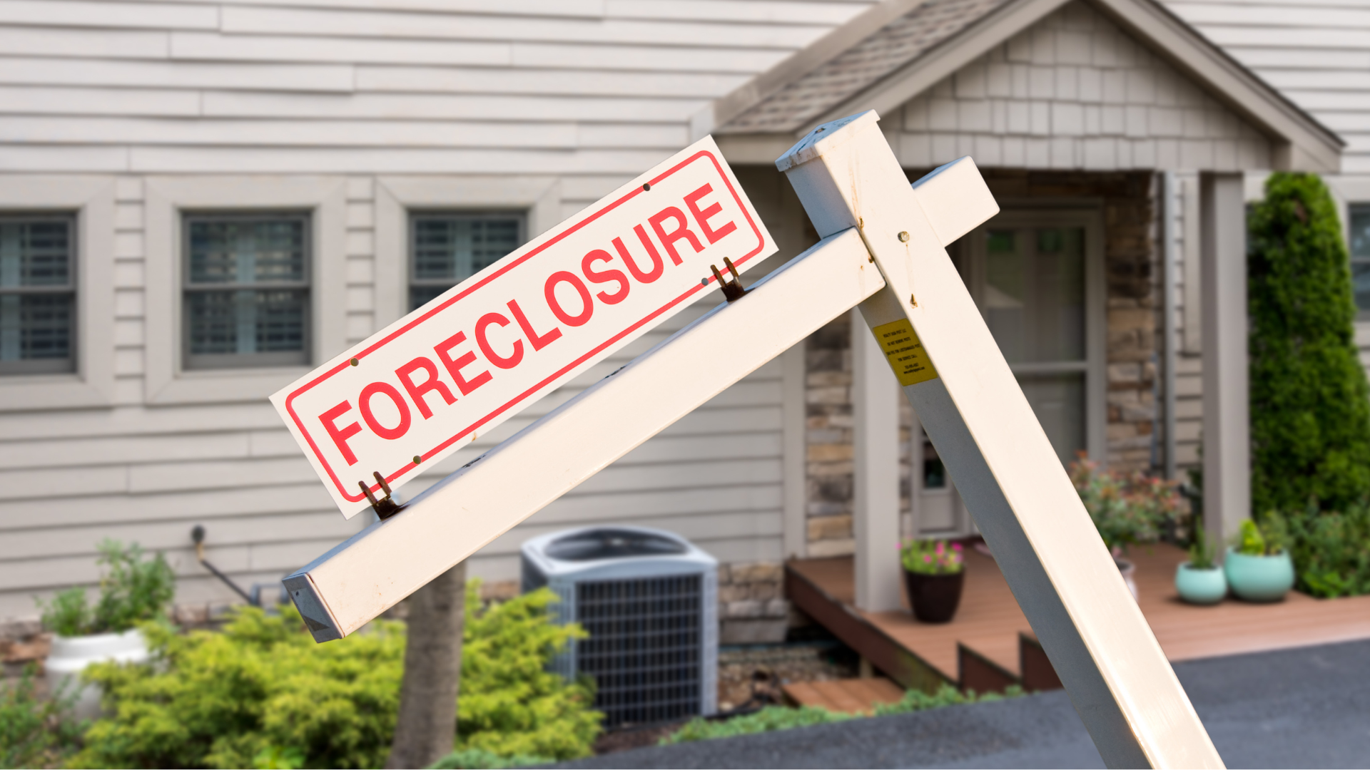 A foreclosure sign is sitting in front of a house.