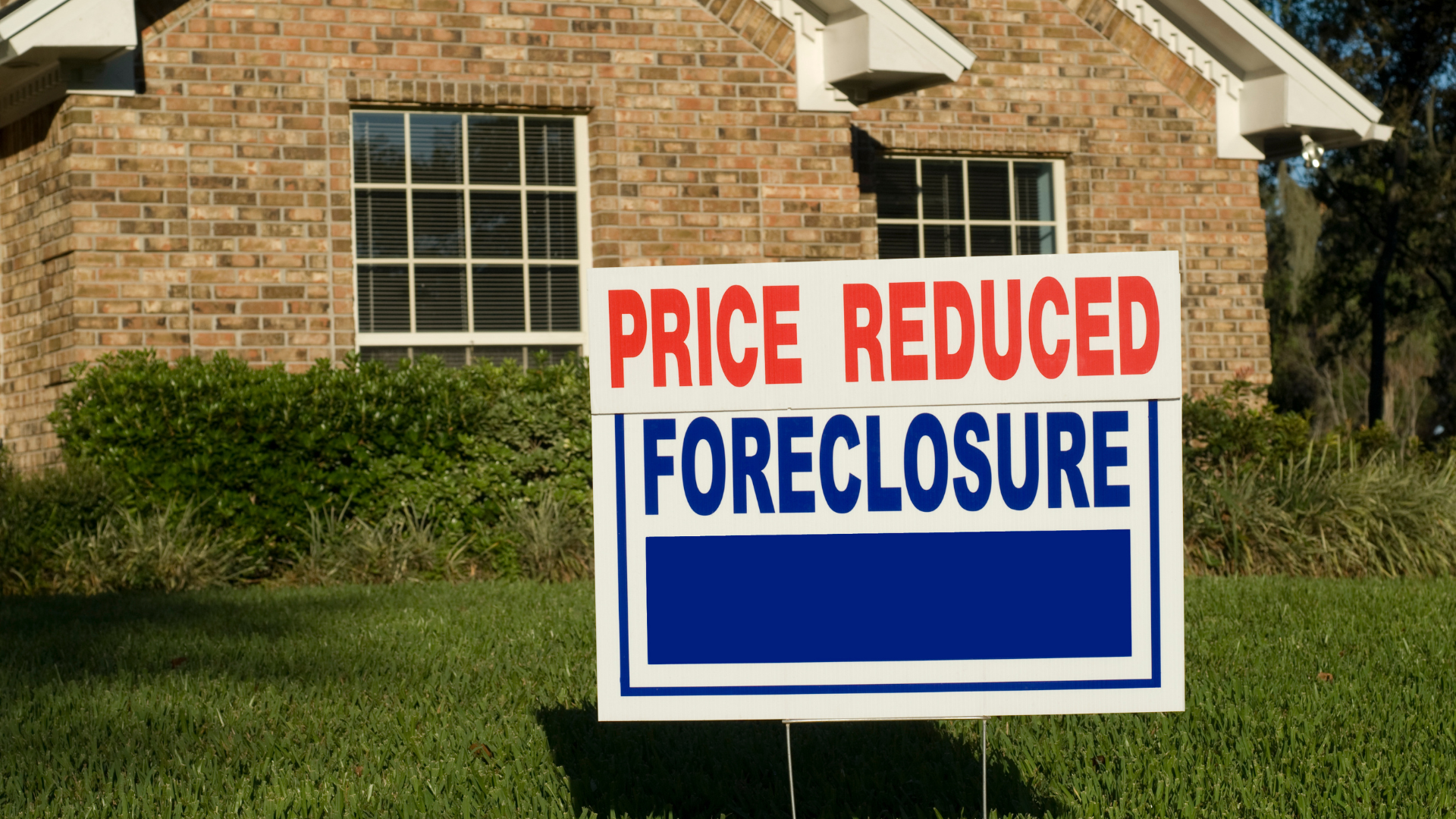 A house with a price reduced foreclosure sign in front of it