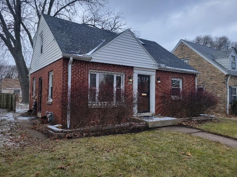 A small franklin brick house with a white siding and a black roof.