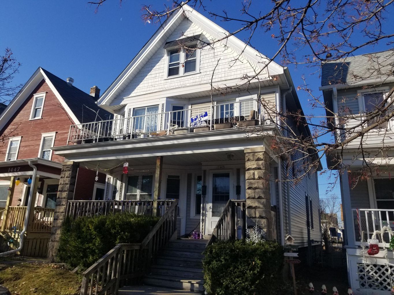 A large greenfield white house with a balcony and stairs