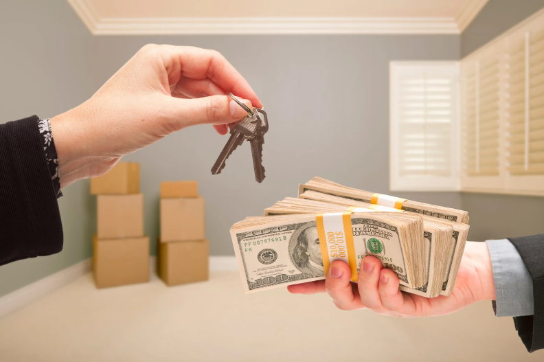 Handing over keys for cash in empty room with moving boxes.
