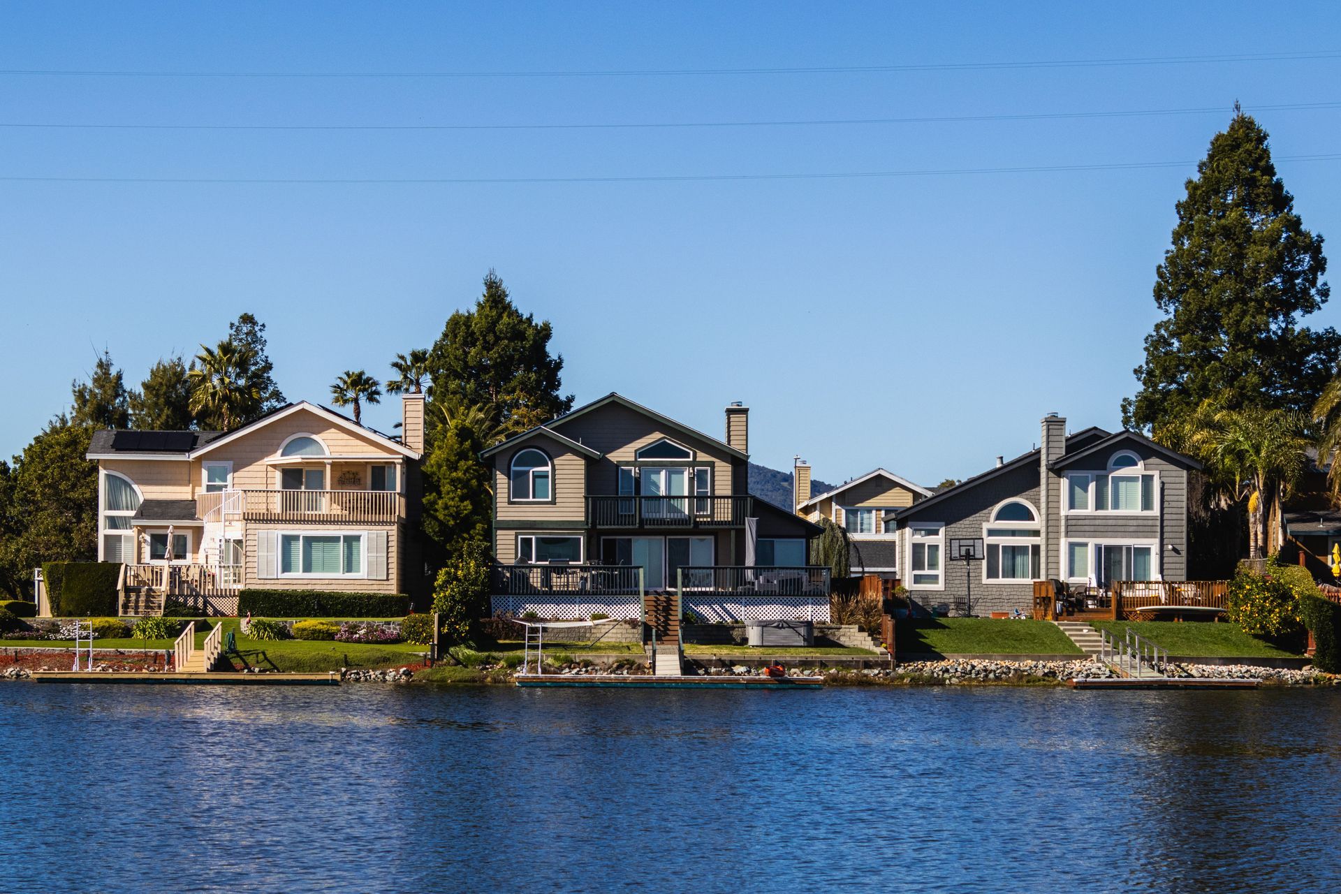 Waterfront homes along a calm blue lake under a clear sky