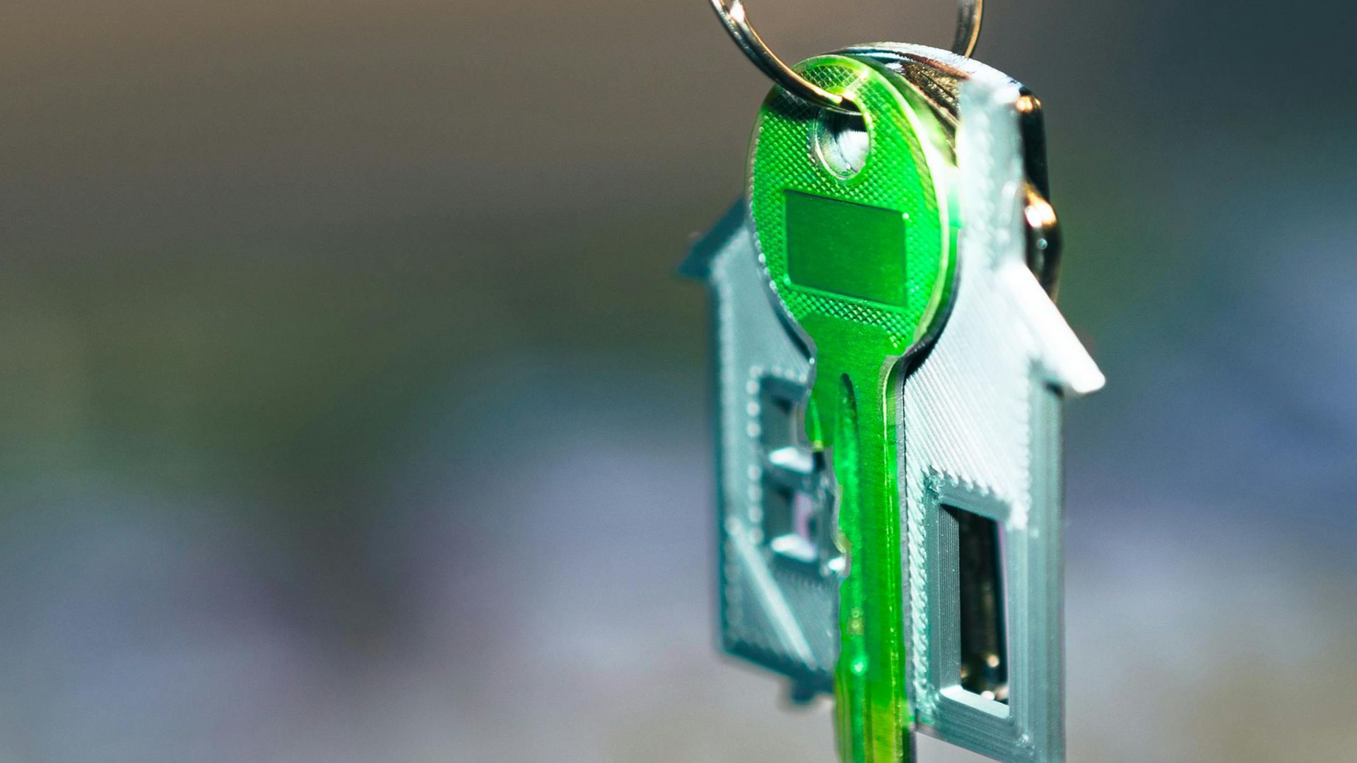 Green key in a keyhole on a door lock, with a metal key ring.