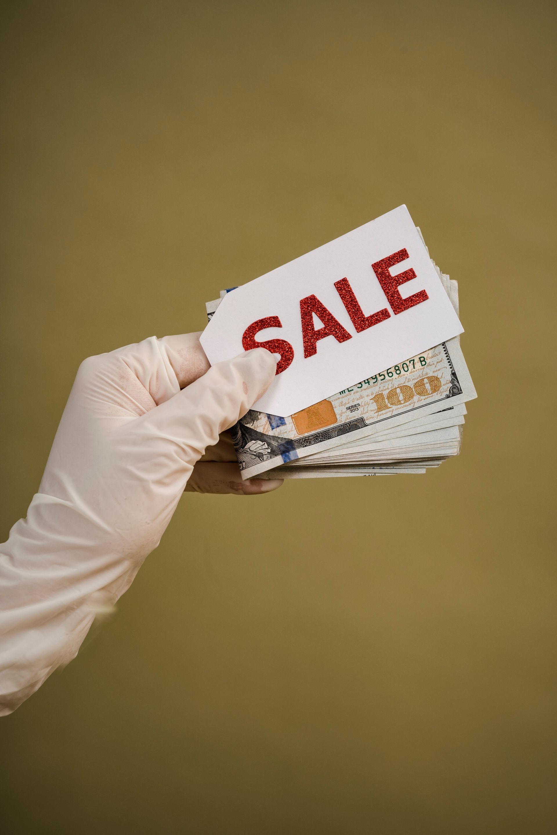 Gloved hand holding discount cards with a red “SALE” label