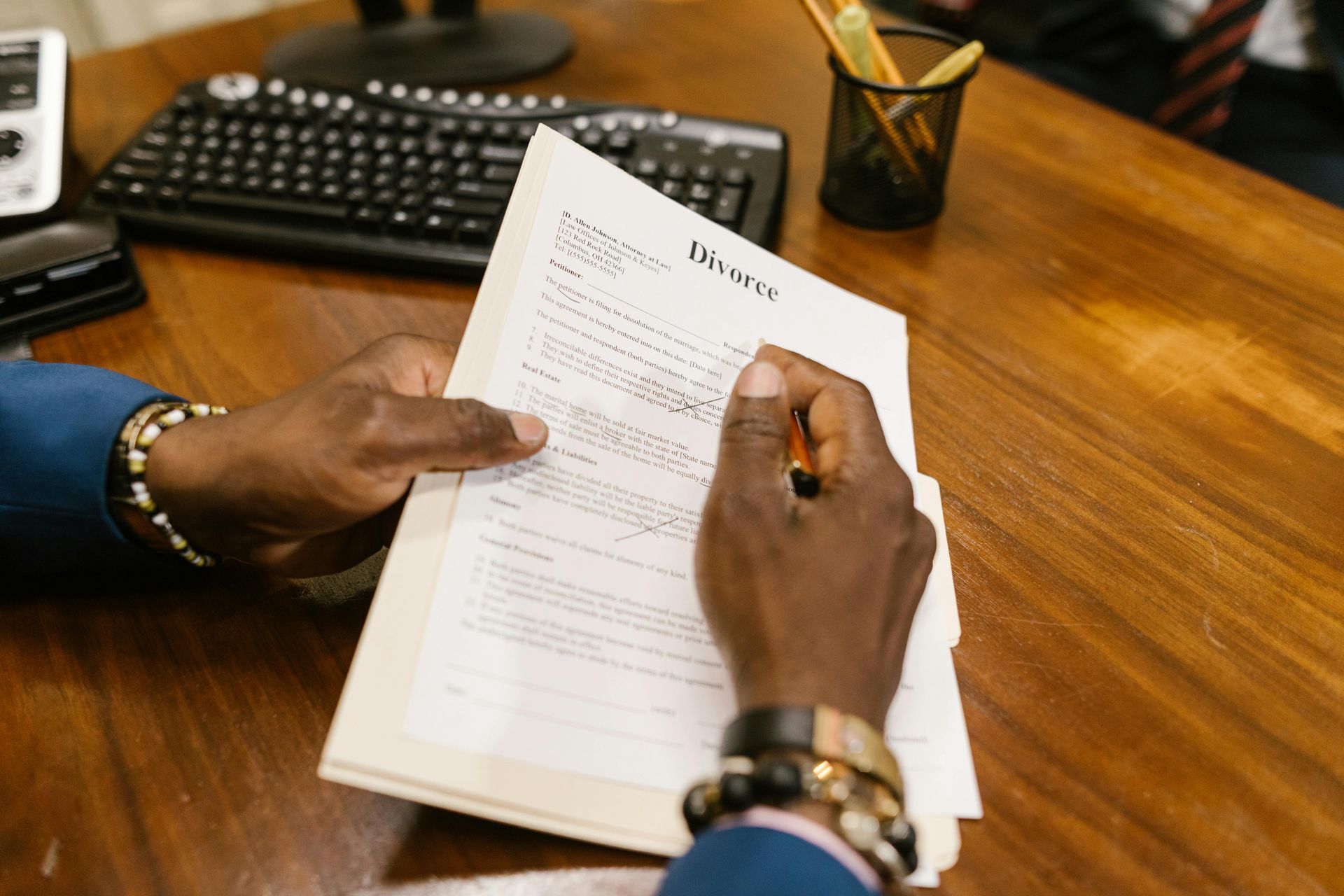 Hands holding and reviewing a stack of paperwork, likely invoices, at a desk.