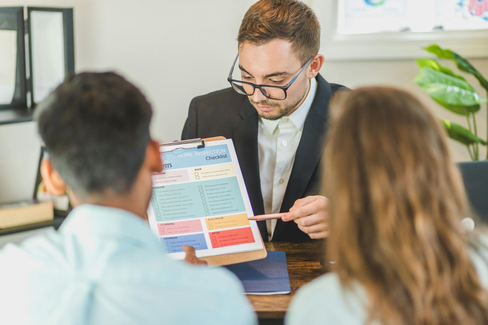 Financial advisor points at paperwork for a couple at a desk.