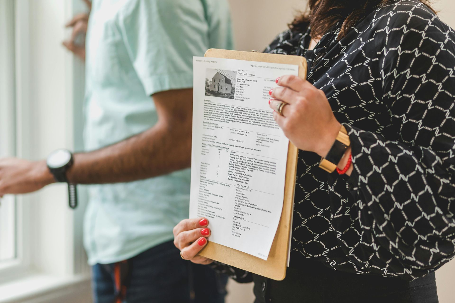 Woman holding documents, looking at a window with a person beside her.