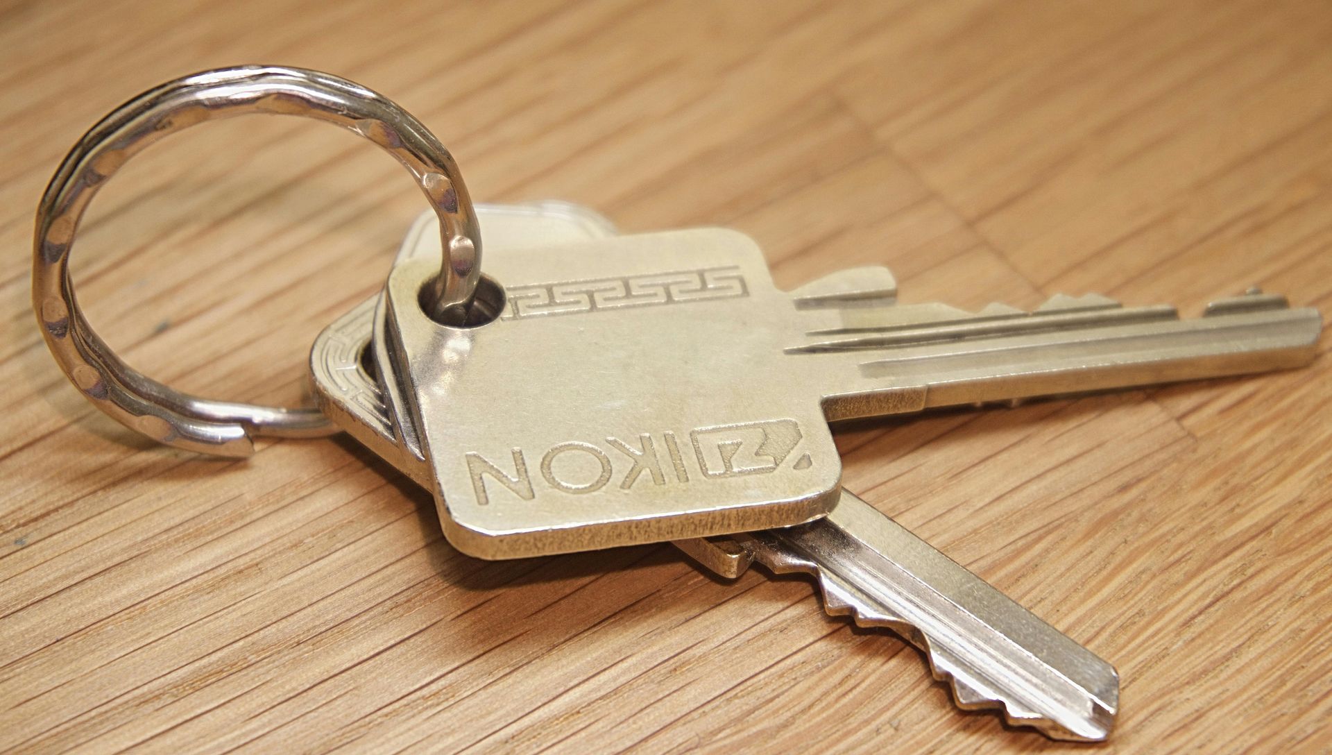 Keys on a ring, resting on a wooden surface. One key has the