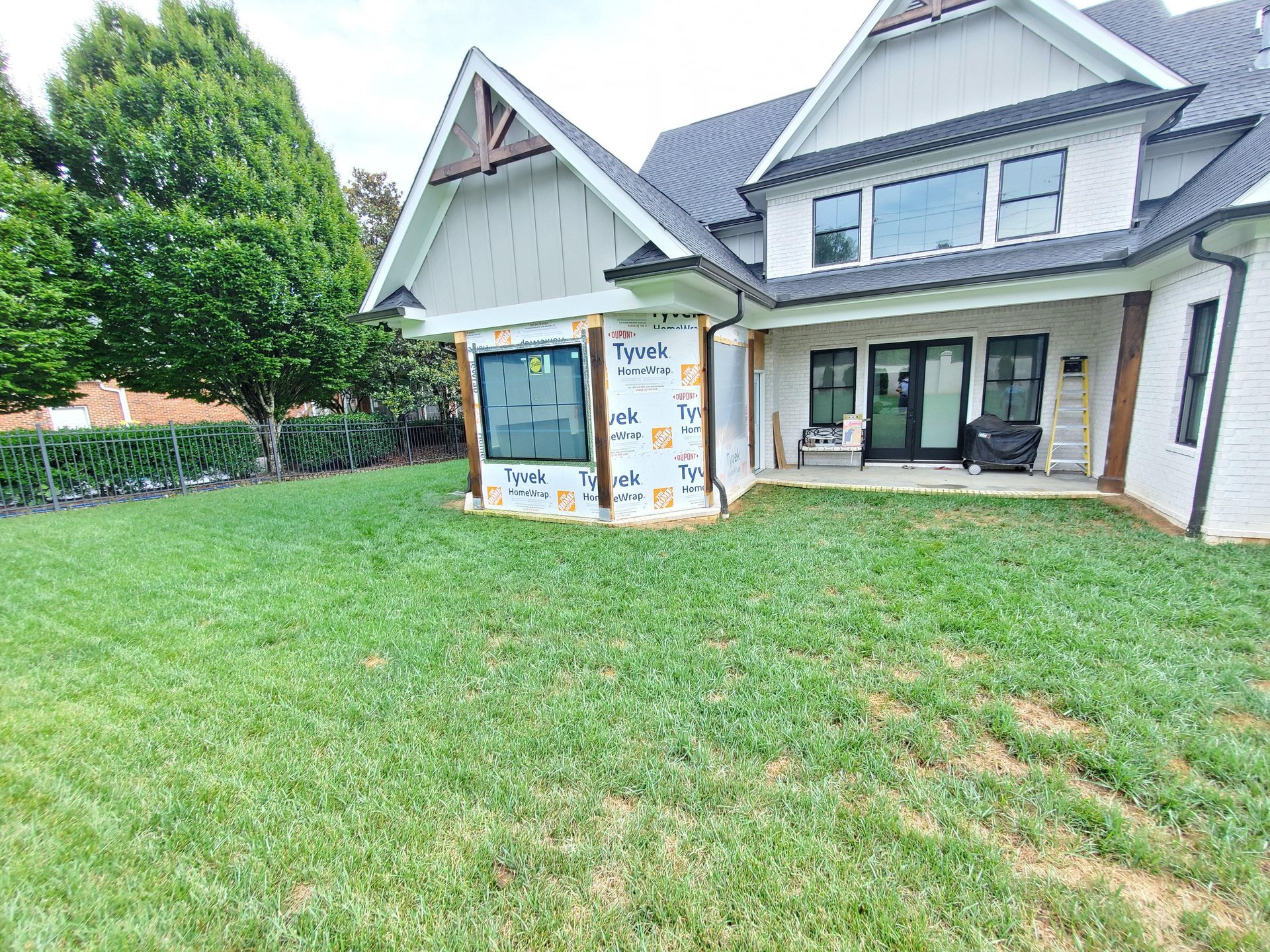 Suburban house with a large green lawn and a stone-front entrance under construction or renovation