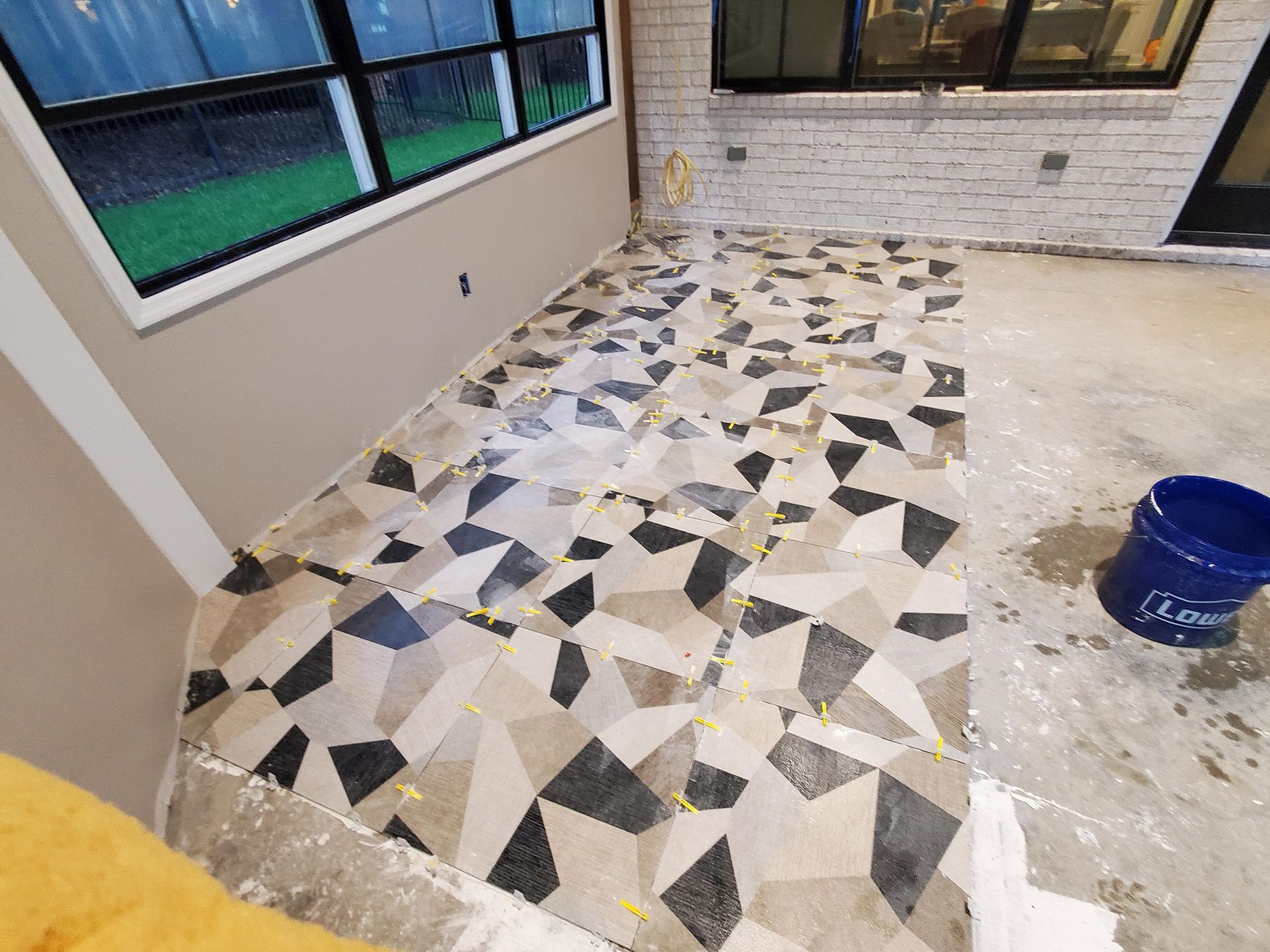 Freshly tiled floor with geometric black, white, and beige pattern in a room under renovation