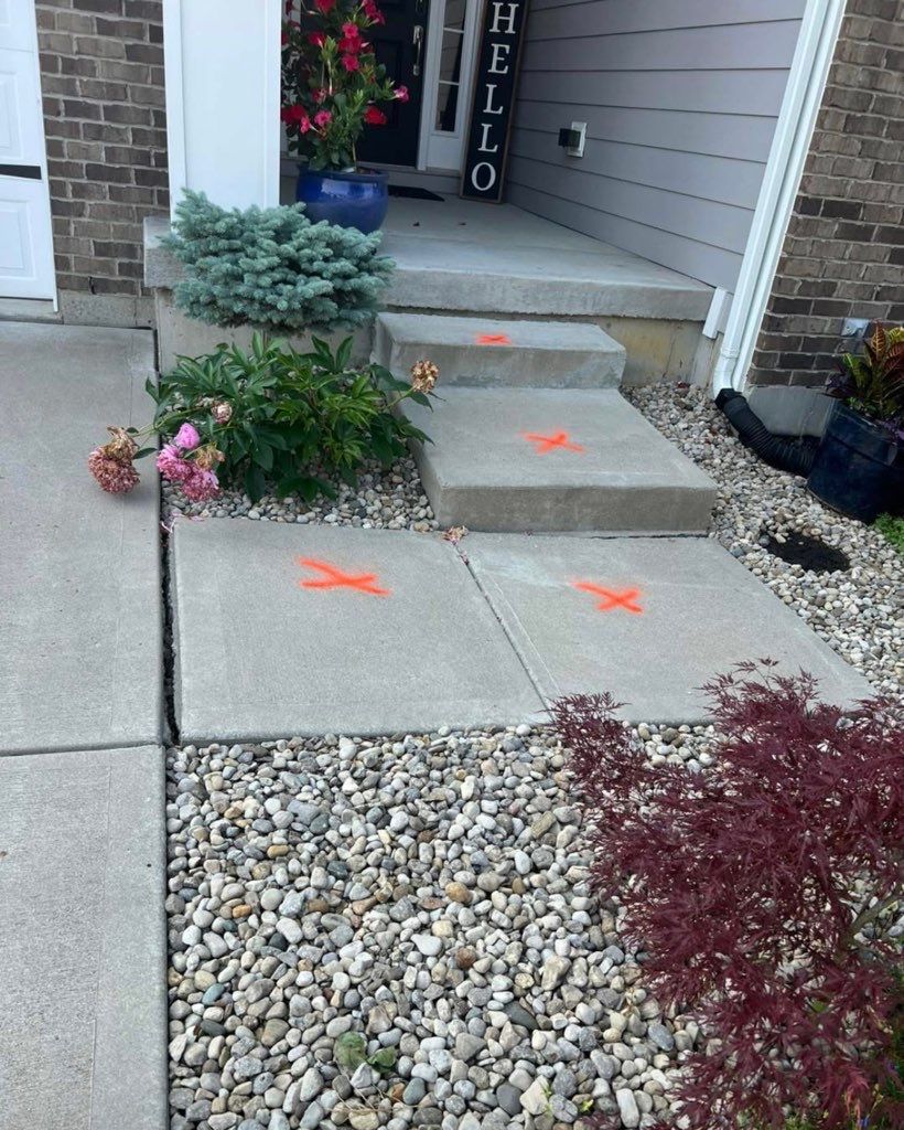 Front entry walkway with concrete steps, orange marking paint, and landscaping stones beside the house