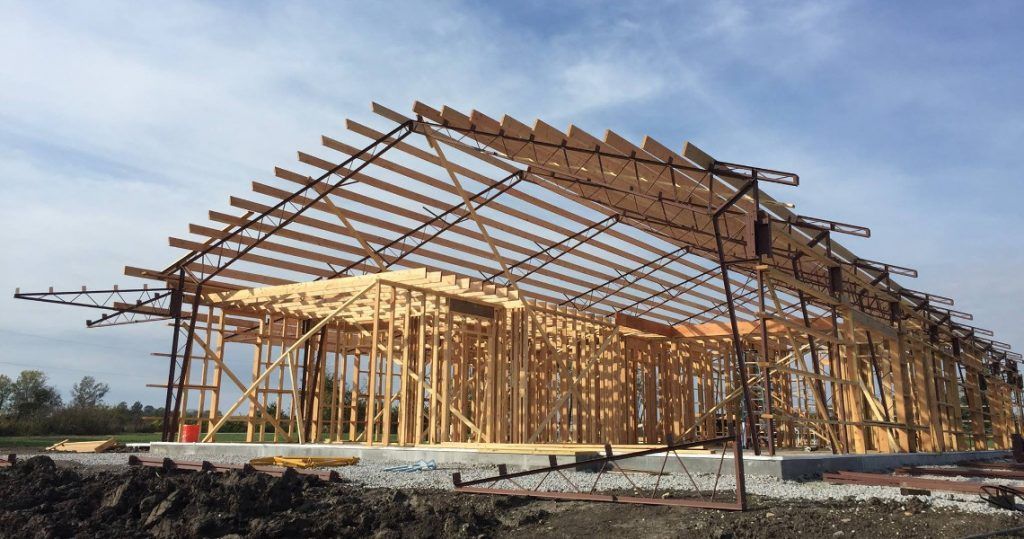 Wooden frame of a building under construction on a cleared site under a clear sky
