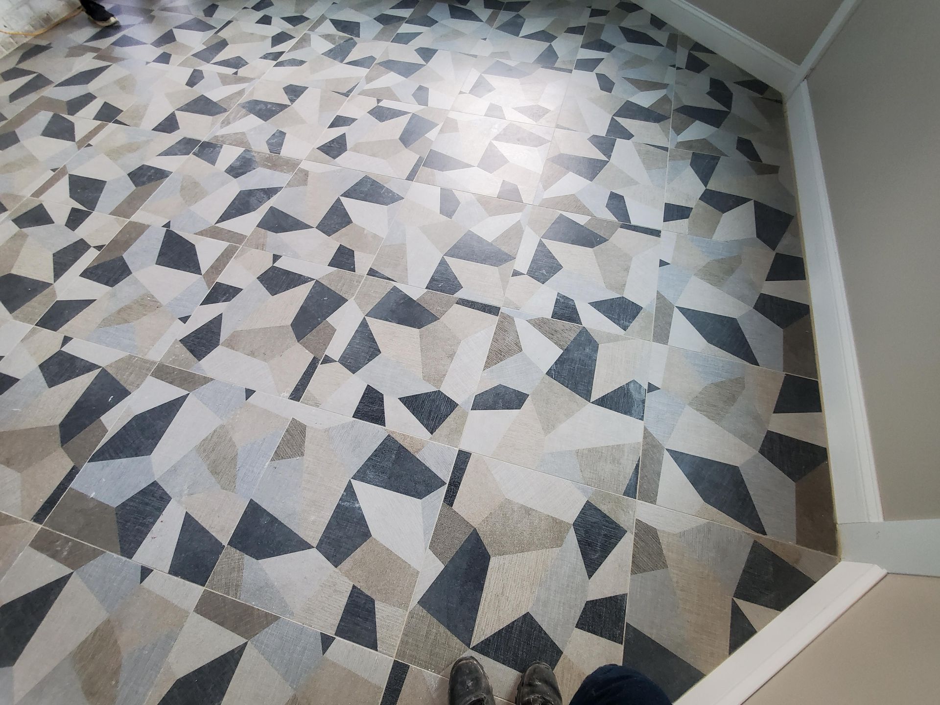 Geometric-patterned carpet in a hallway corner with gray, beige, and black tiles