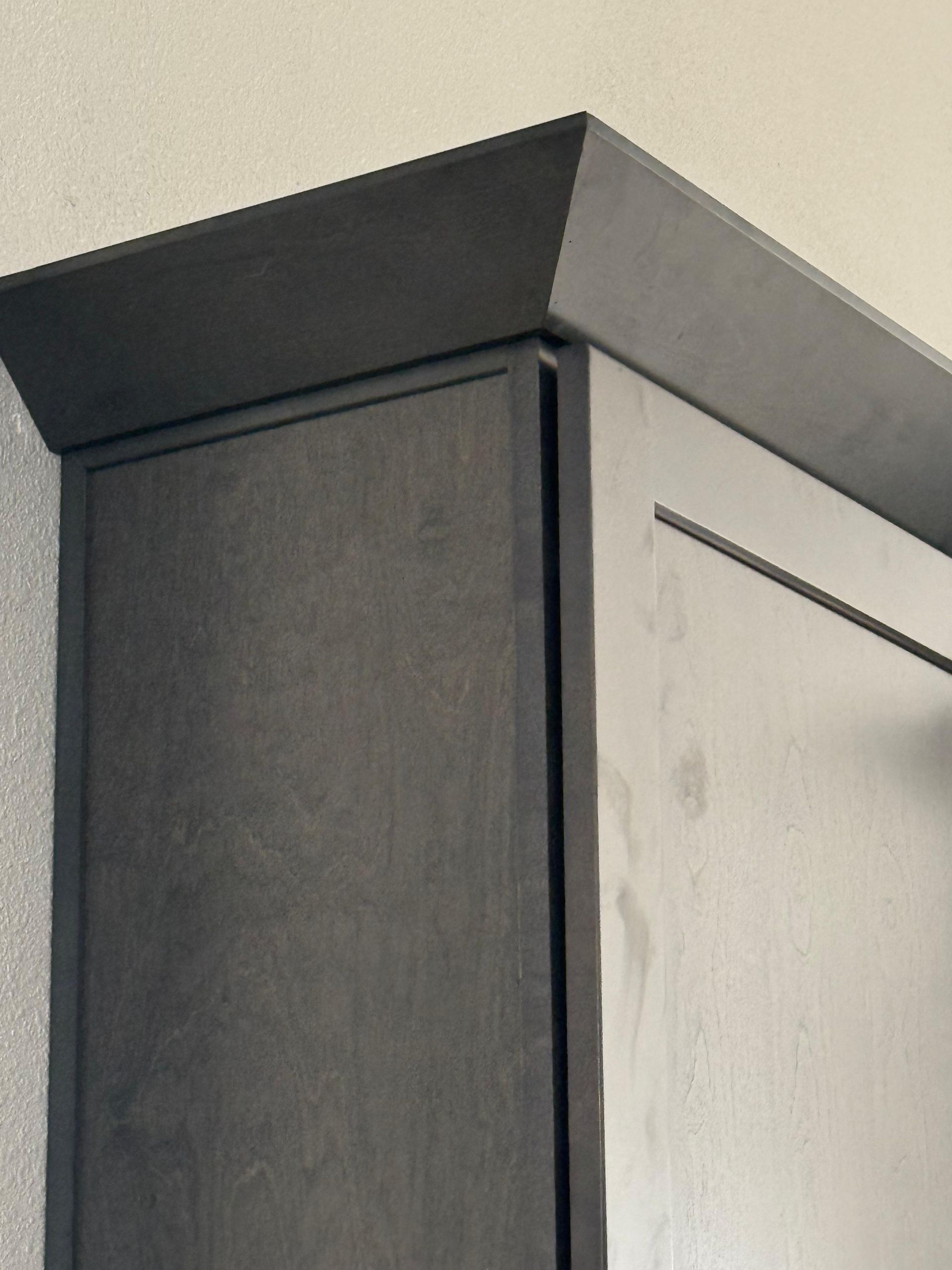 Close-up of a dark wood cabinet with a gray top against a light wall.