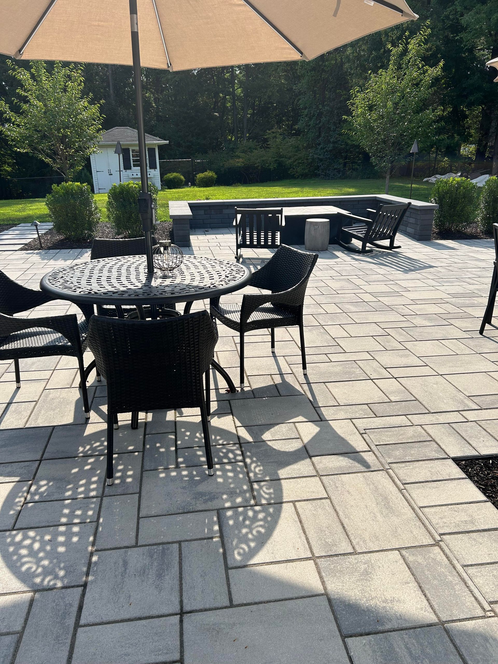 Patio with black metal chairs and tables under umbrellas on a sunny stone terrace