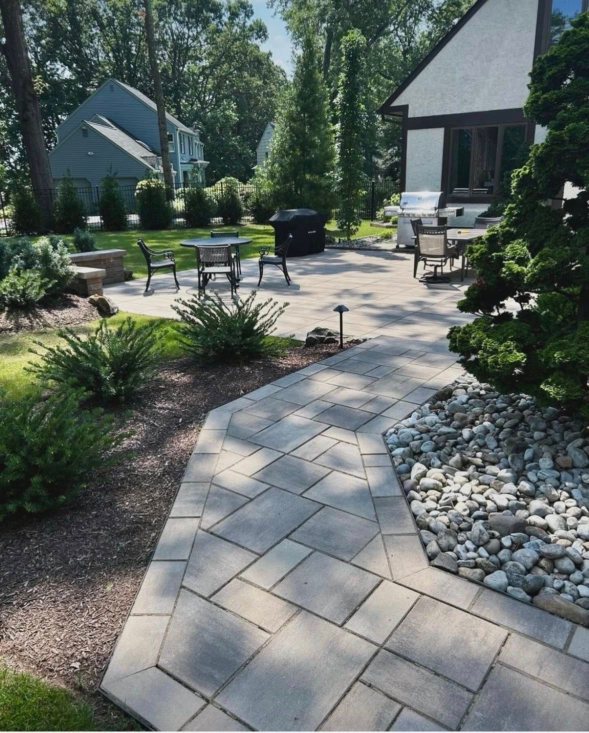 Backyard patio with stone path, outdoor seating, and landscaped garden beds