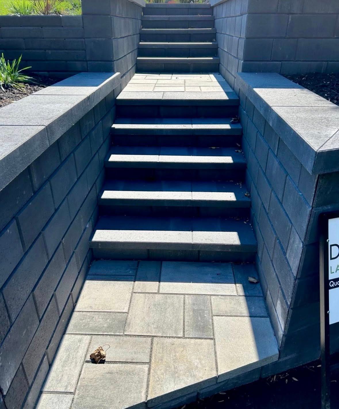 Outdoor stone steps between gray retaining walls, with no accessible ramp visible.