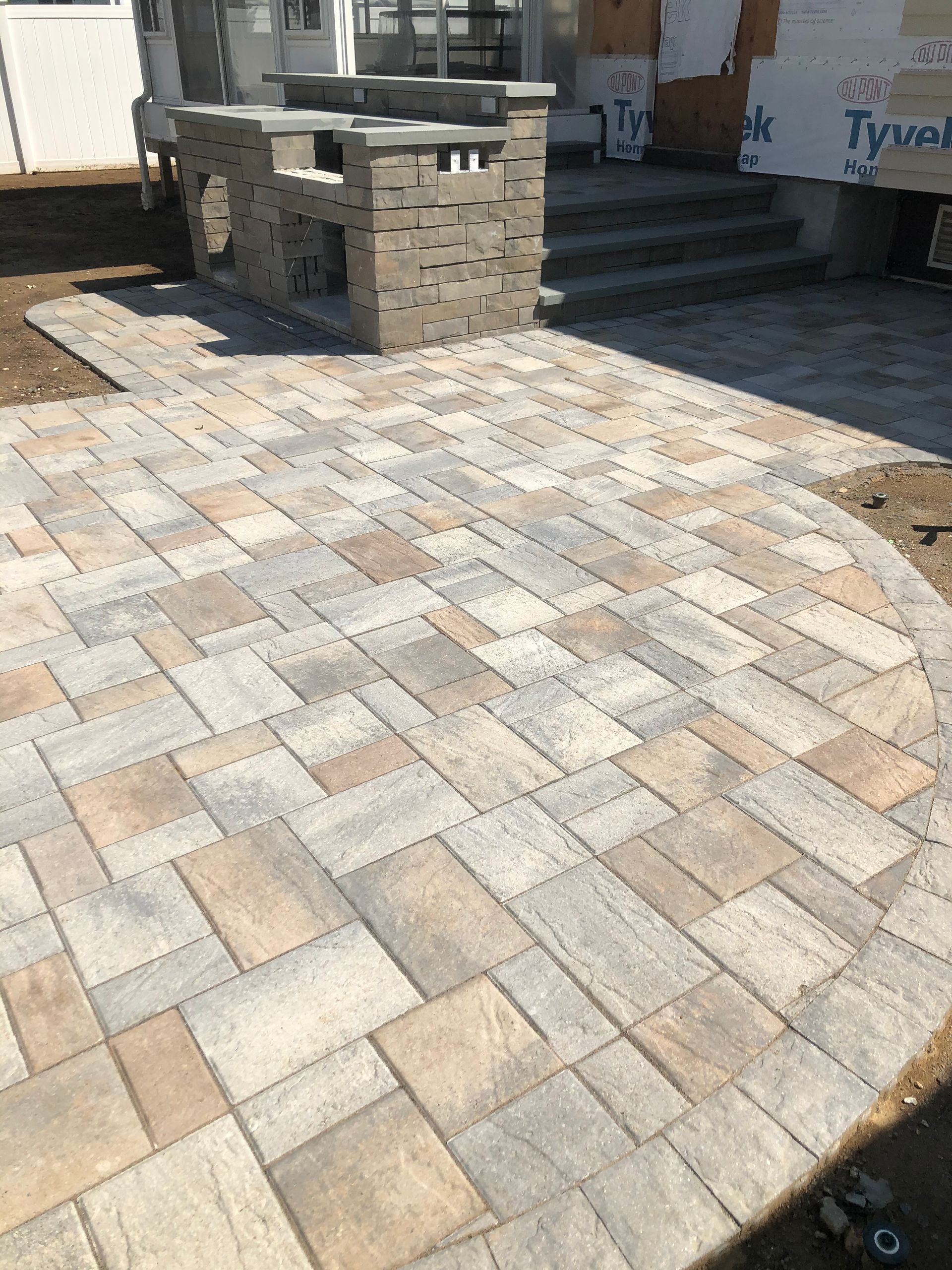 Stone-paver courtyard with a built-in brick grill and steps leading to a house entrance