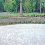 Curved cobblestone path beside green grass and trees in a park