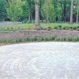 Curved stone path beside a green park with trees and shrubs
