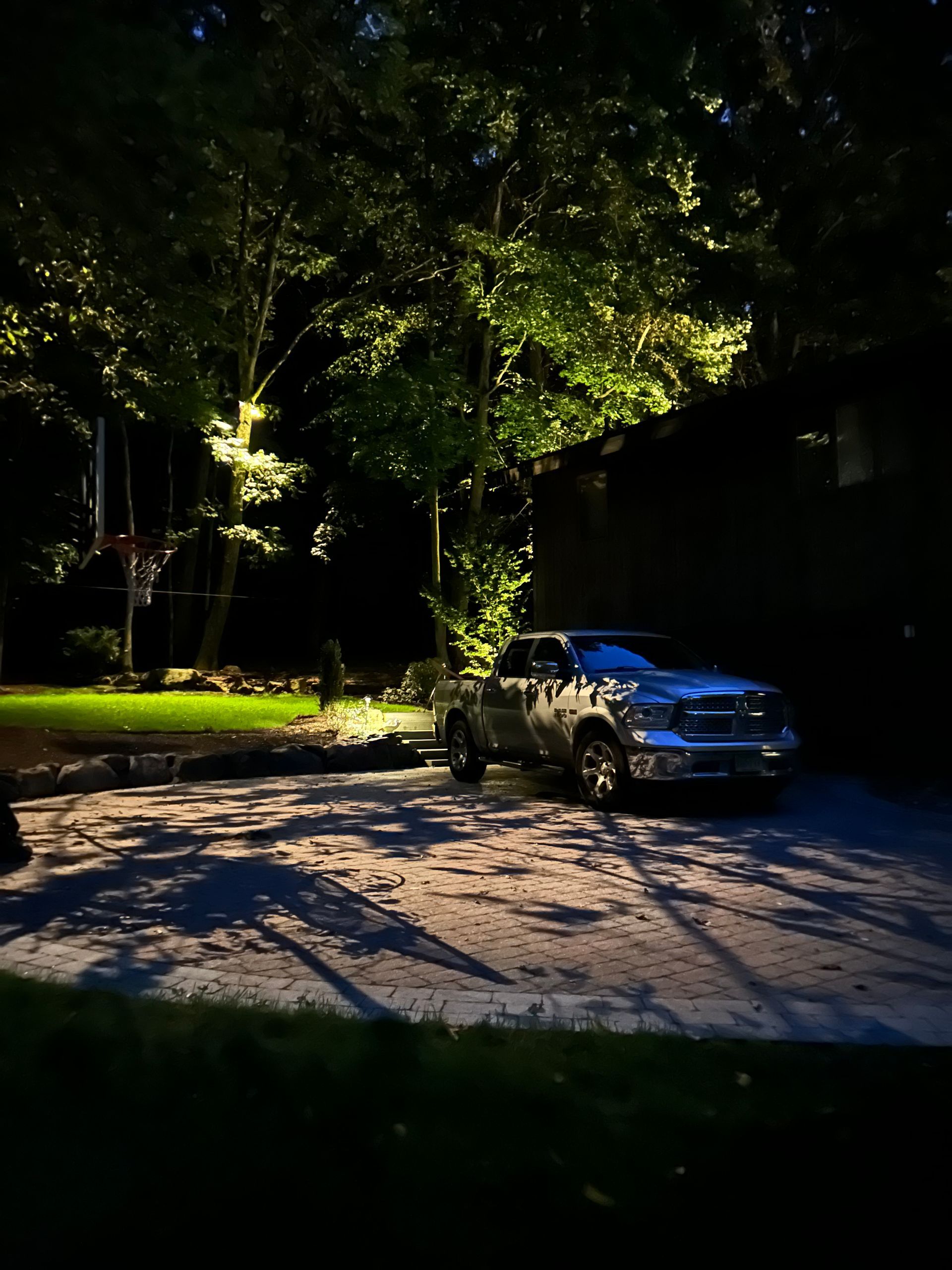 Night street with a parked SUV under trees and strong shadows.