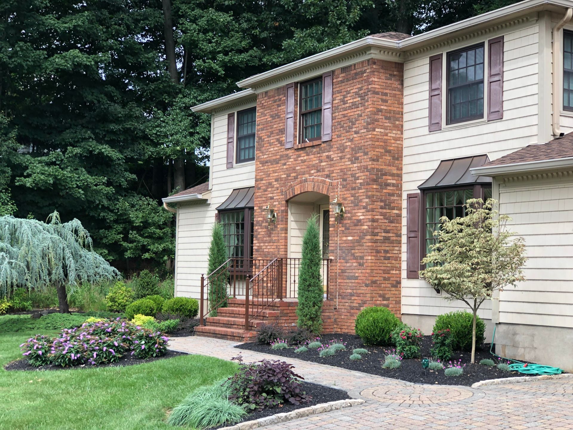 Two-story brick and cream house with landscaped front yard and curved stone walkway.