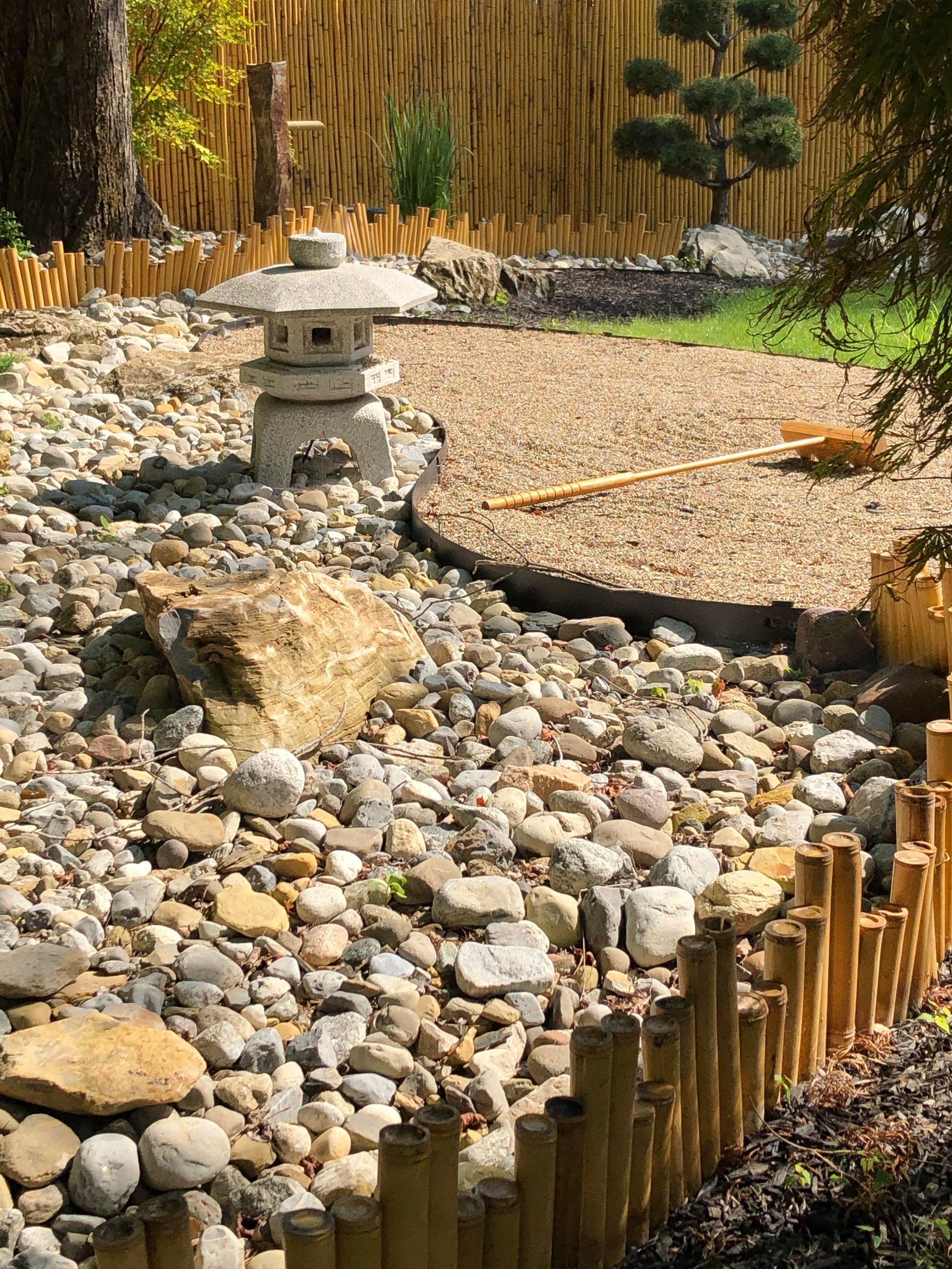Zen rock garden with pebbles, bamboo edging, and a small stone lantern.