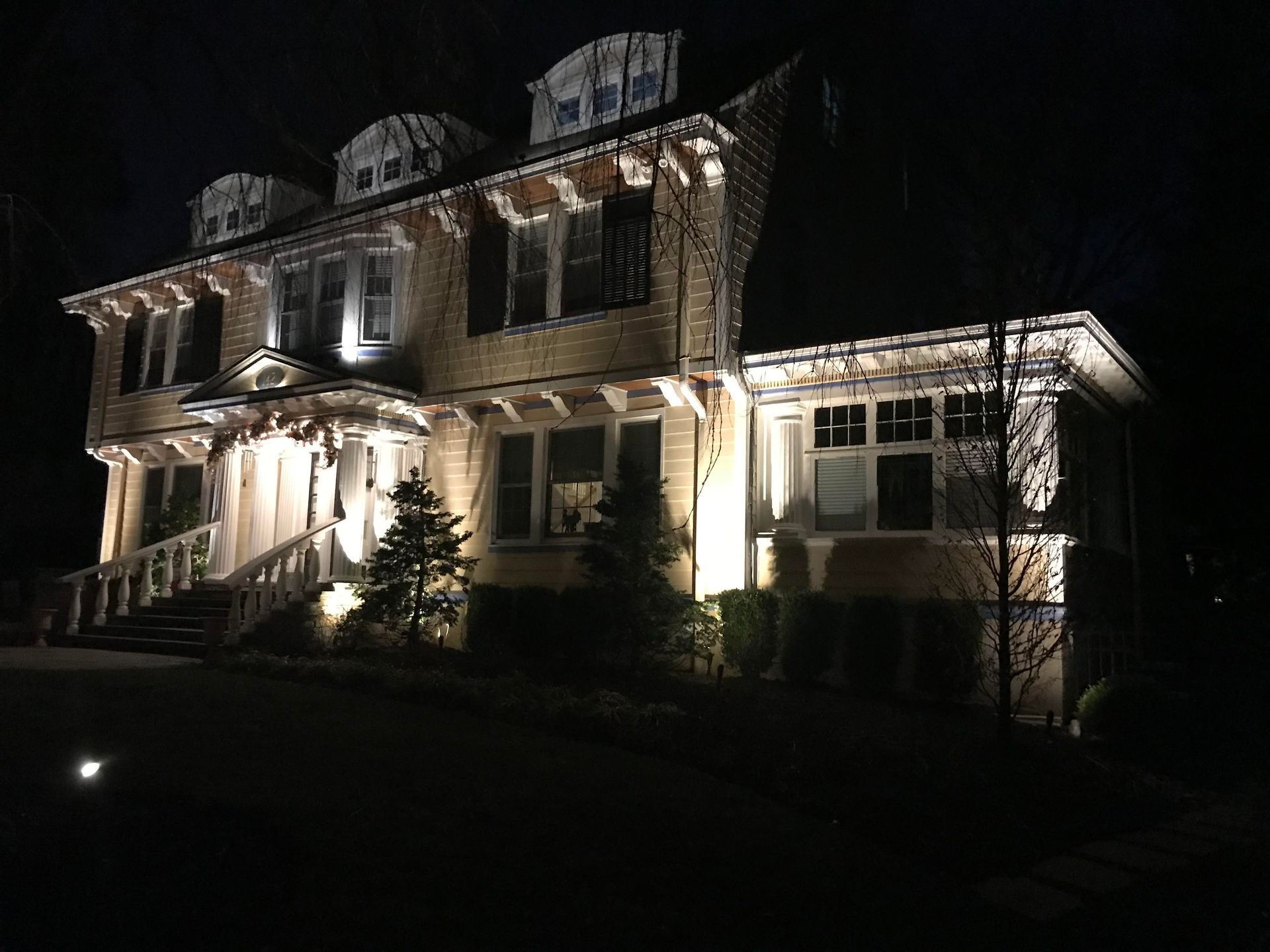 Large house lit up at night with glowing windows and porch lights