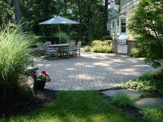 Patio with table, umbrella, grill, and landscaped garden path beside a house