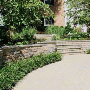 Curved stone steps and retaining wall beside a landscaped garden and brick building