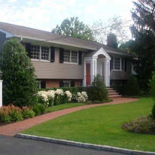 Suburban house with white columns, brick walkway, and green lawn in front yard