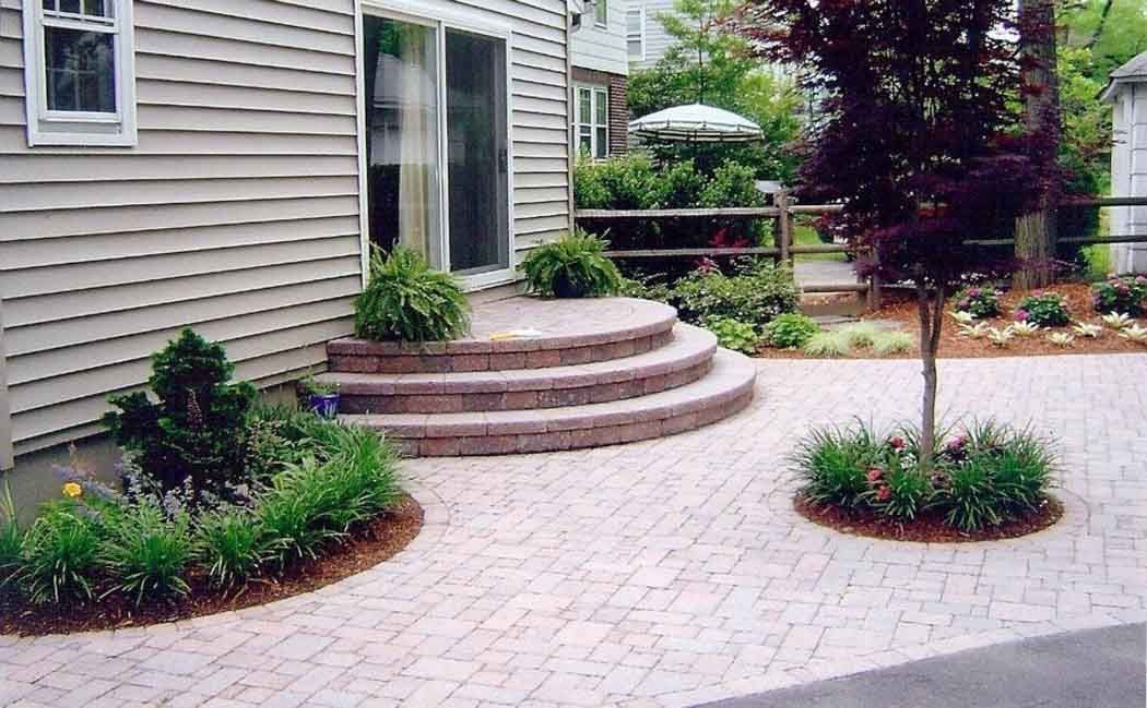 Stone patio steps and landscaped garden beside a house with siding and a window