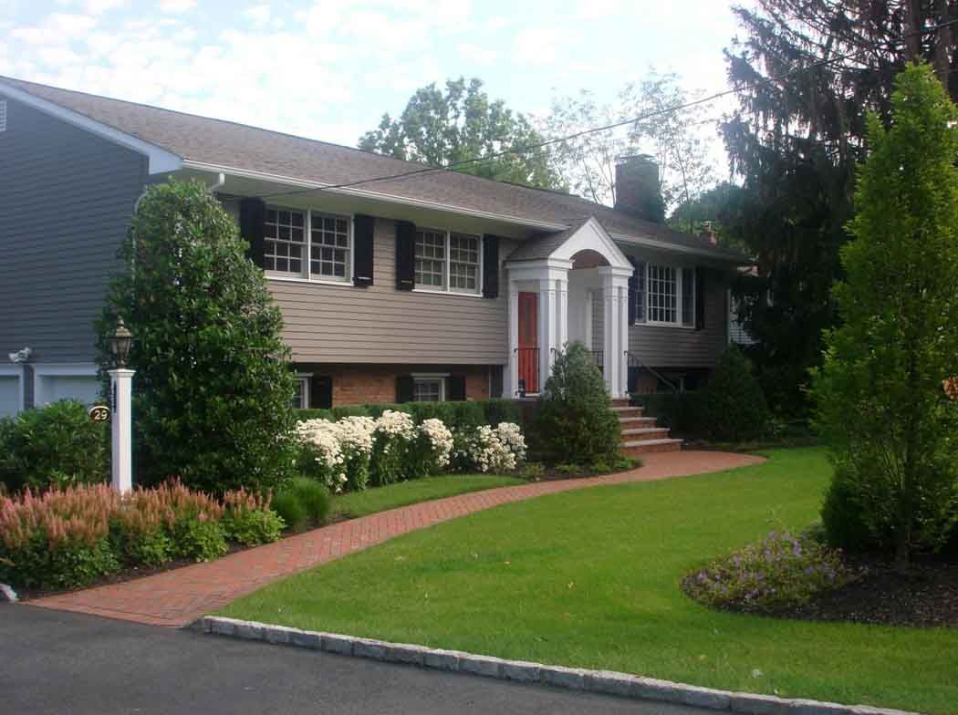 Suburban split-level house with red door, white trim, and manicured lawn and garden