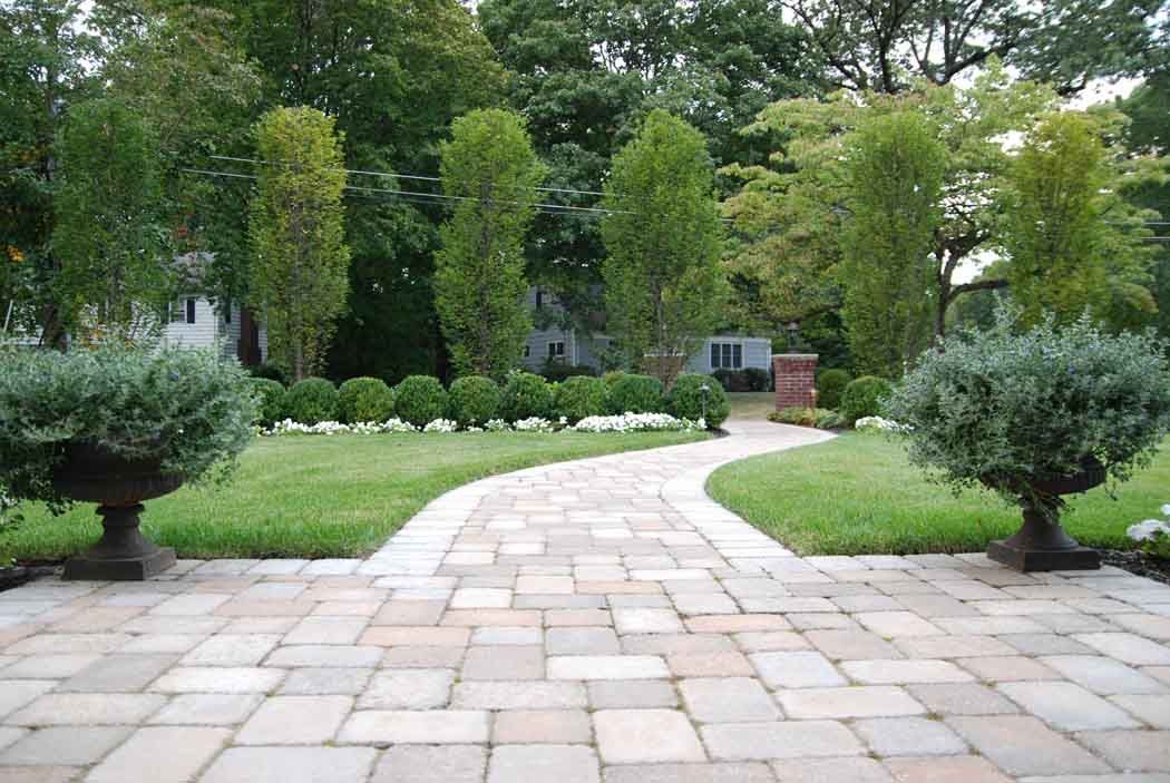 Curved stone path through a green garden with trees and shrubs