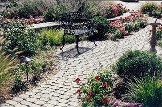Garden path with a wrought-iron bench, surrounded by flowers and shrubs