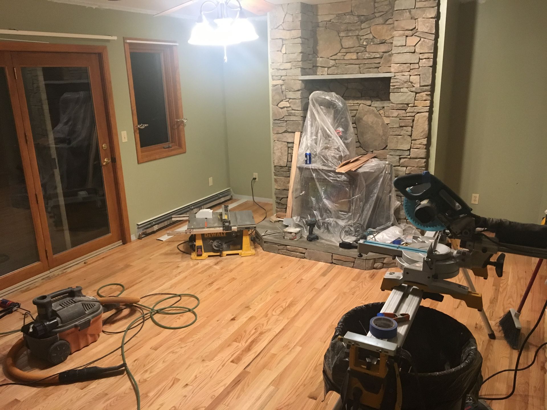 A living room with hardwood floors and a stone fireplace.
