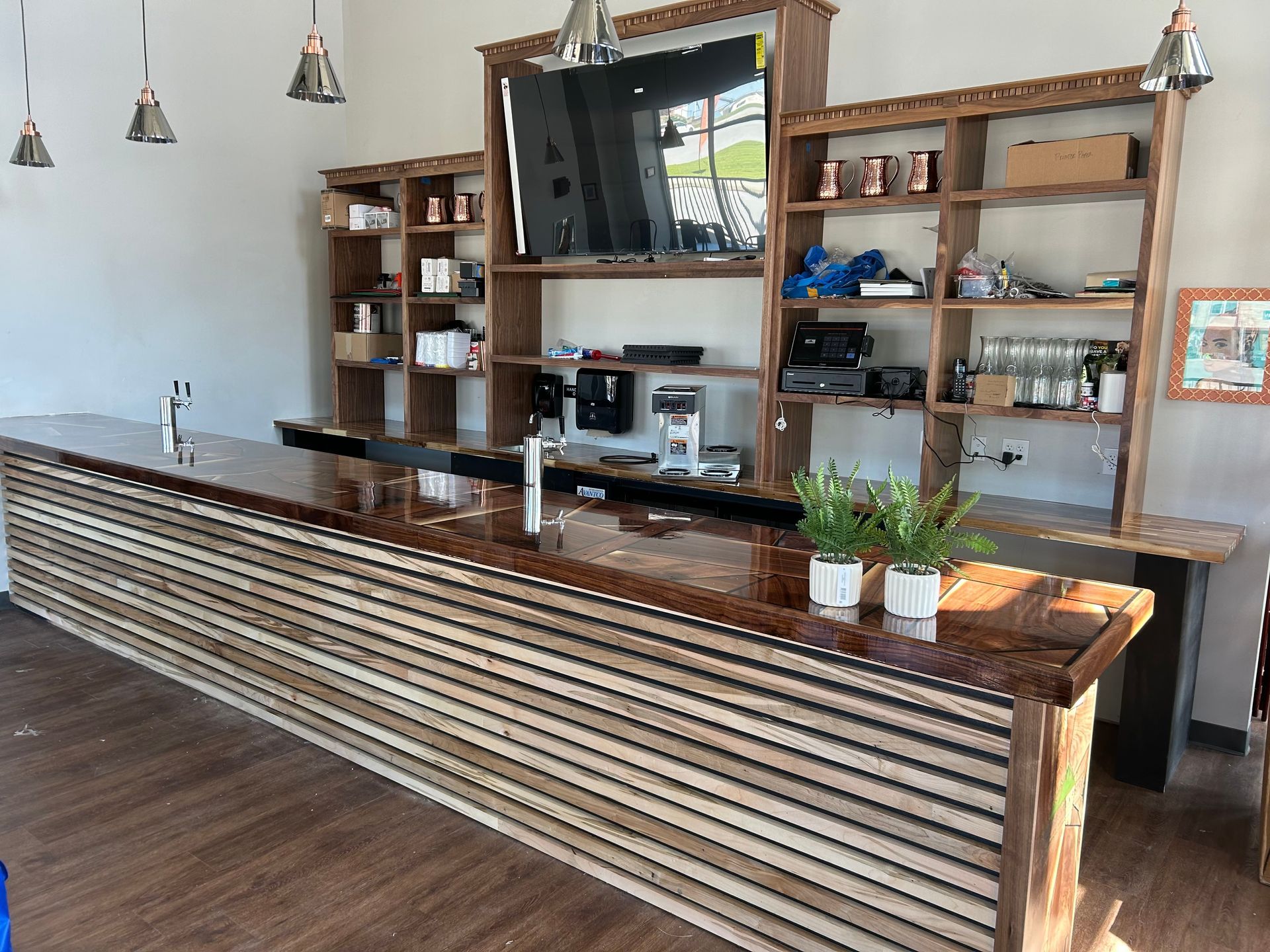 A kitchen with a long wooden counter top and shelves.
