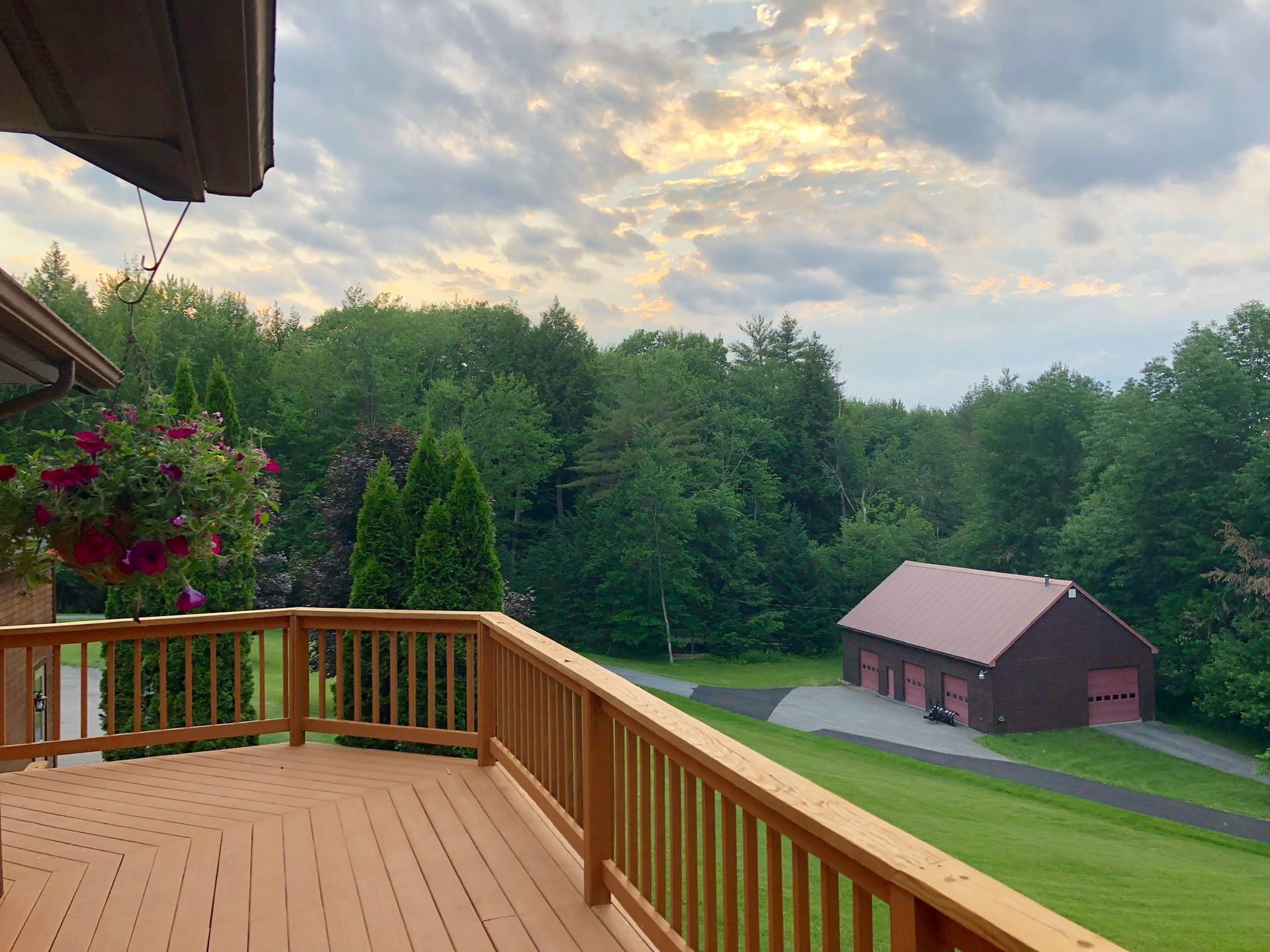 A wooden deck with a view of a barn and trees.