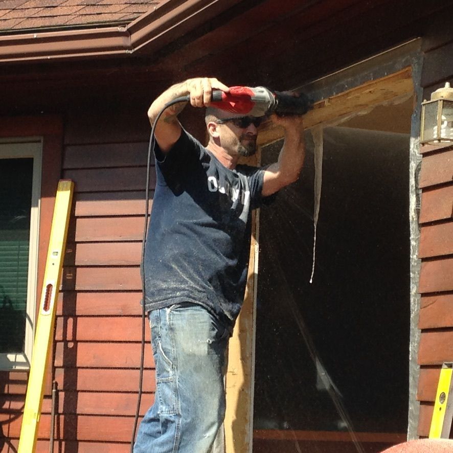 A man is using a drill to fix a door