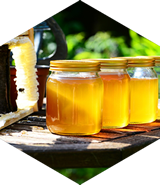 Three jars of honey are sitting on a wooden table.