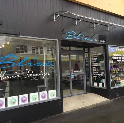 Bliss Hair Design storefront with sign above door and products on display. Dark blue exterior.