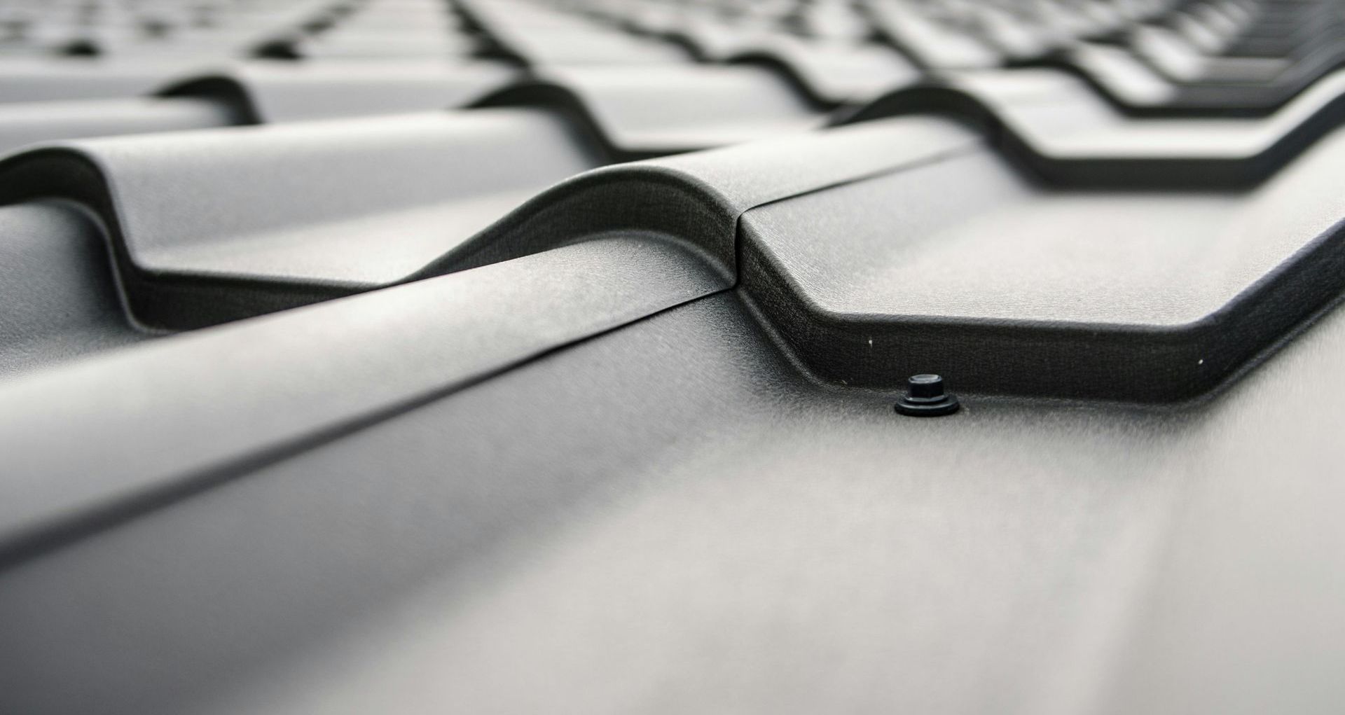 A close up of a black roof with a screw in it.