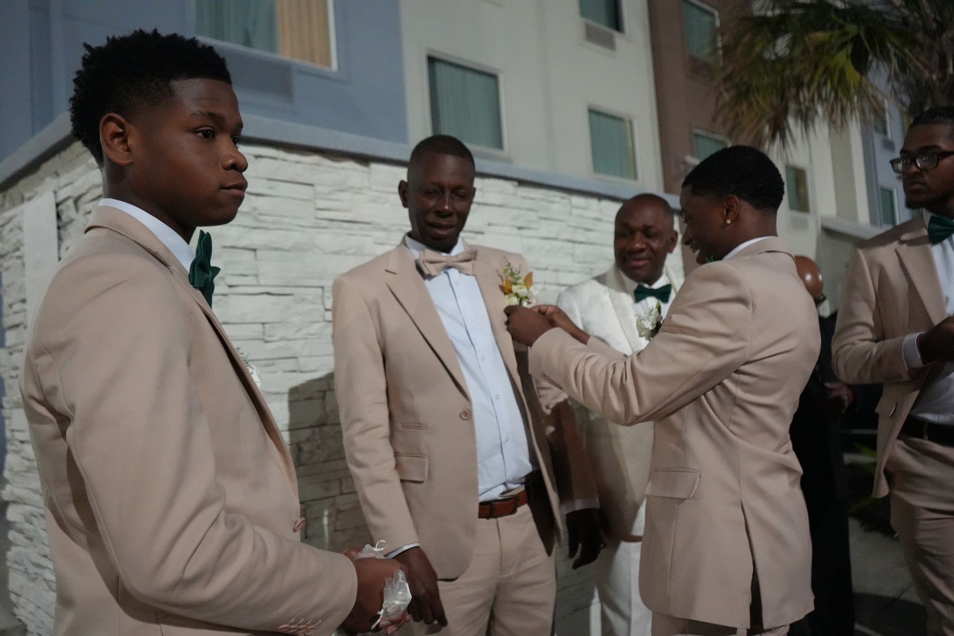 A group of men in suits and bow ties are standing in front of a building.