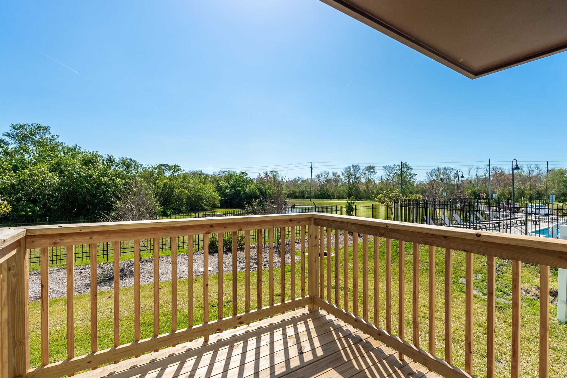 a balcony with a wooden railing overlooking a lush green field at Whitney Place Apartments in Clearwater, FL.