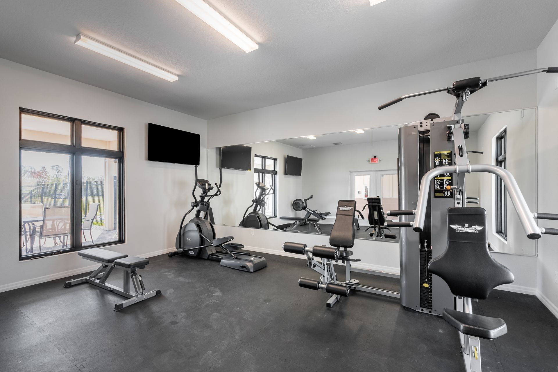 a gym with a lot of equipment and a large mirror at Whitney Place Apartments in Clearwater, FL.