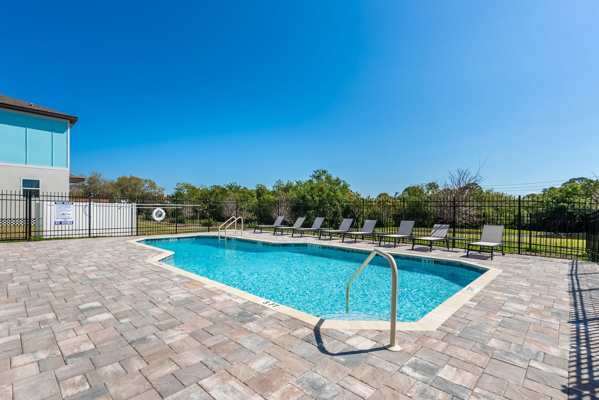 a large swimming pool surrounded by chairs and a fence at Whitney Place Apartments in Clearwater, FL.