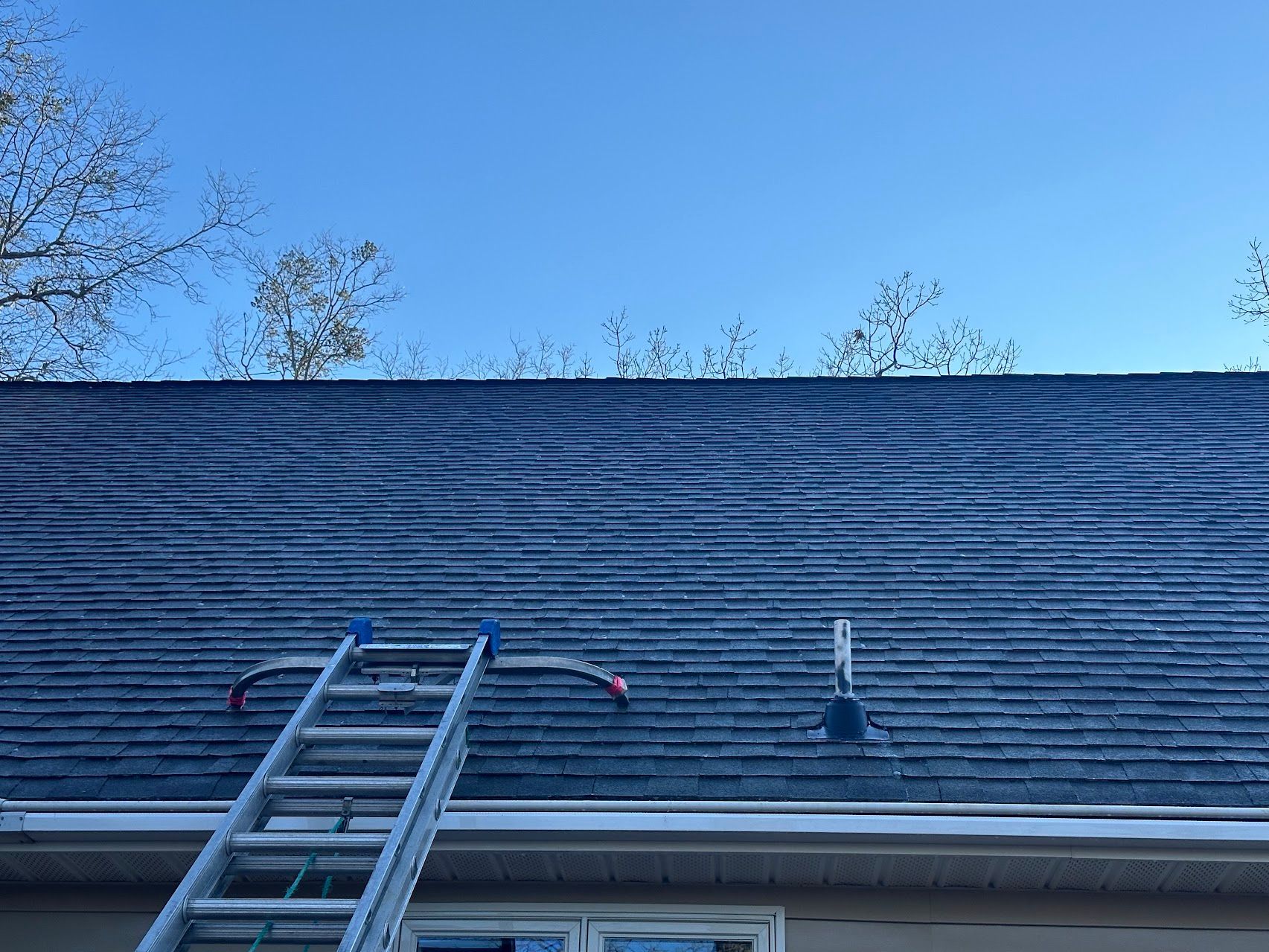 A ladder is sitting on the roof of a house.