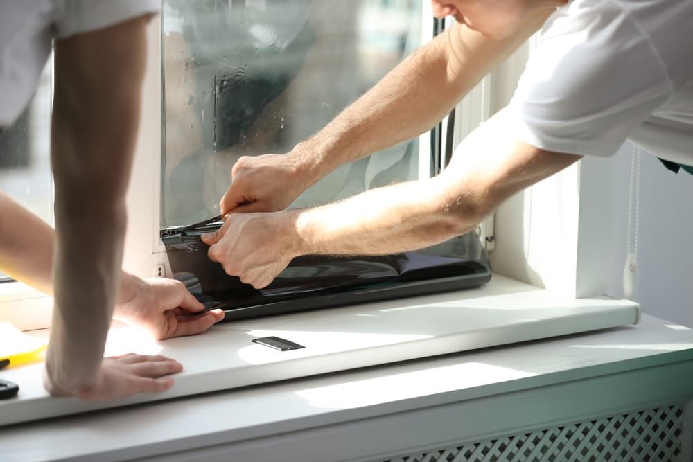 Two People Installing Window Tint on A Window — Local Glassmaster in Huskisson, NSW