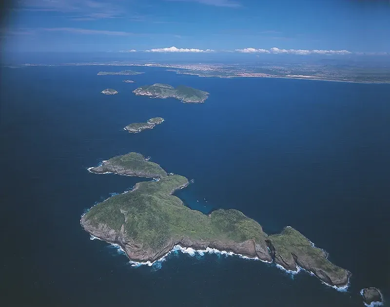 Vista aérea de várias ilhas verdes em um oceano azul escuro sob um céu limpo.